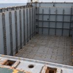 AI-generated illustration of an empty container ship hold with vertical cell guides and hatch coaming