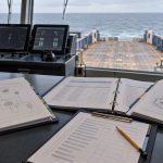 AI-generated illustration of technical binders and a review checklist on an offshore vessel bridge overlooking the aft work deck